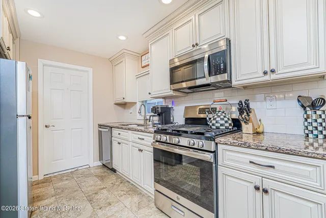 a kitchen with stainless steel appliances granite countertop white cabinets a stove top oven and a granite counter tops