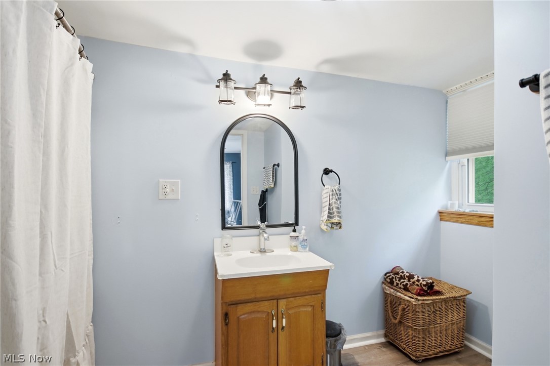 2591 Wayland Road Deerfield, OH 44411 - Photo 17 of 46 Bathroom featuring a single vanity with wood-finish cabinetry, a white countertop, and a chrome faucet
