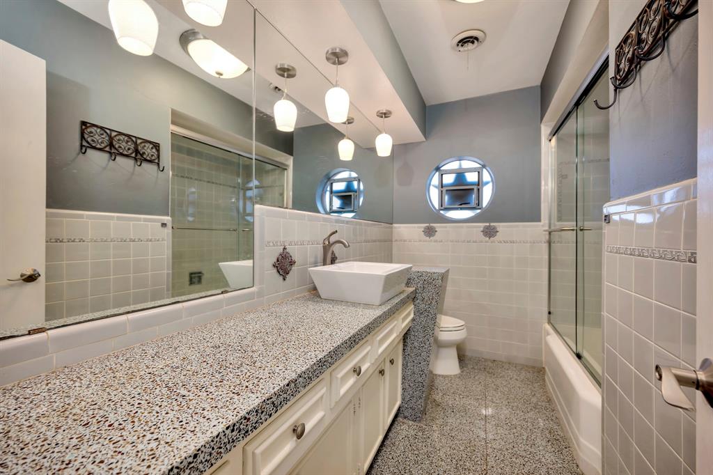 10005 Ridgehaven Drive Dallas, TX 75238 - Photo 16 of 27 a bathroom with a granite countertop sink a toilet and shower