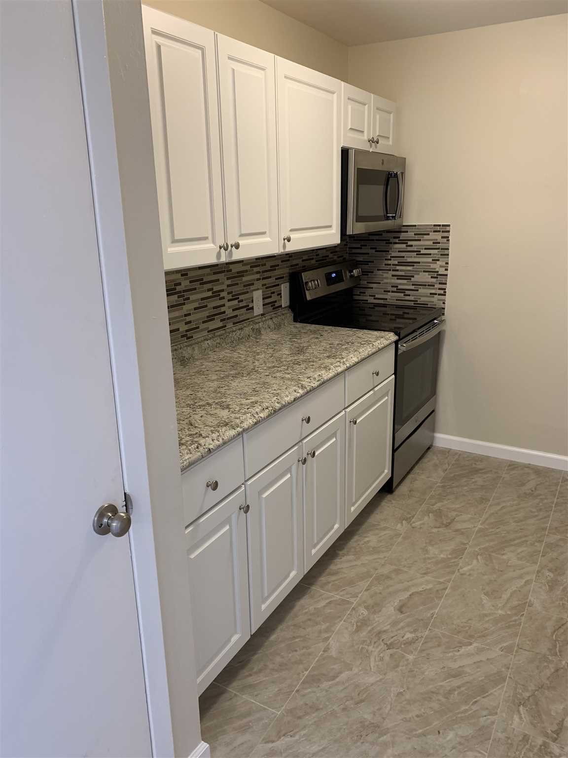 10 White Gate Road, Unit J Wappingers Falls, NY 12590 - Photo 3 of 11 a kitchen with stainless steel appliances granite countertop a stove a sink and a microwave