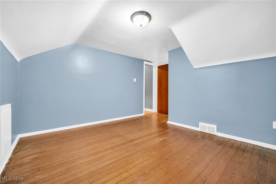 1605 Laclede Road Cleveland, OH 44121 - Photo 22 of 40 Additional living space with wood-type flooring, vaulted ceiling, visible vents, and baseboards
