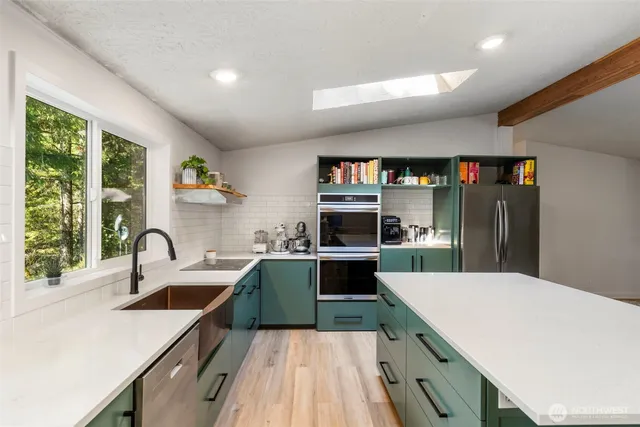 a kitchen with kitchen island a counter top space a sink stainless steel appliances and cabinets