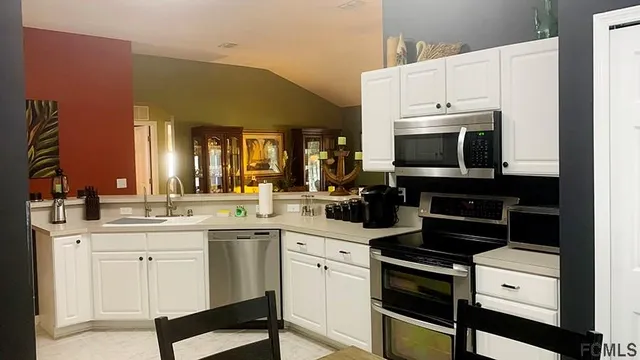 a kitchen with stainless steel appliances kitchen island granite countertop dining table chair and a refrigerator