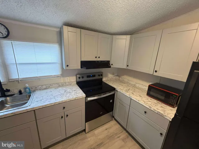 a kitchen with granite countertop white cabinets and a stove