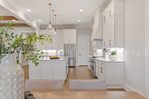 a kitchen with stainless steel appliances kitchen island granite countertop a stove a sink and a white cabinets
