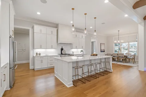 a large white kitchen with kitchen island a sink white cabinets and stainless steel appliances