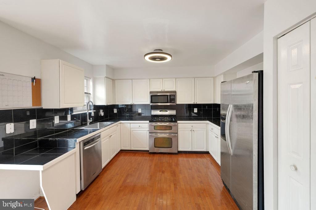 9823 Sherwood Farm Road Owings Mills, MD 21117 - Photo 6 of 29 a kitchen with a sink a stove top oven and white stainless steel appliances