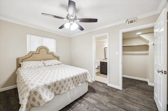 a bedroom with a bed and dresser with wooden floor
