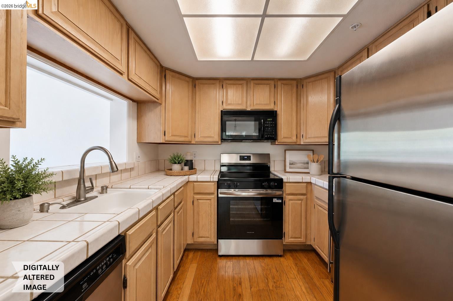 261 Redhawk Road Novato, CA 94949 - Photo 4 of 47 Kitchen featuring wood-finish flooring, light wood cabinetry, stainless steel appliances, a tiled countertop, and a built-in ceiling light panel
