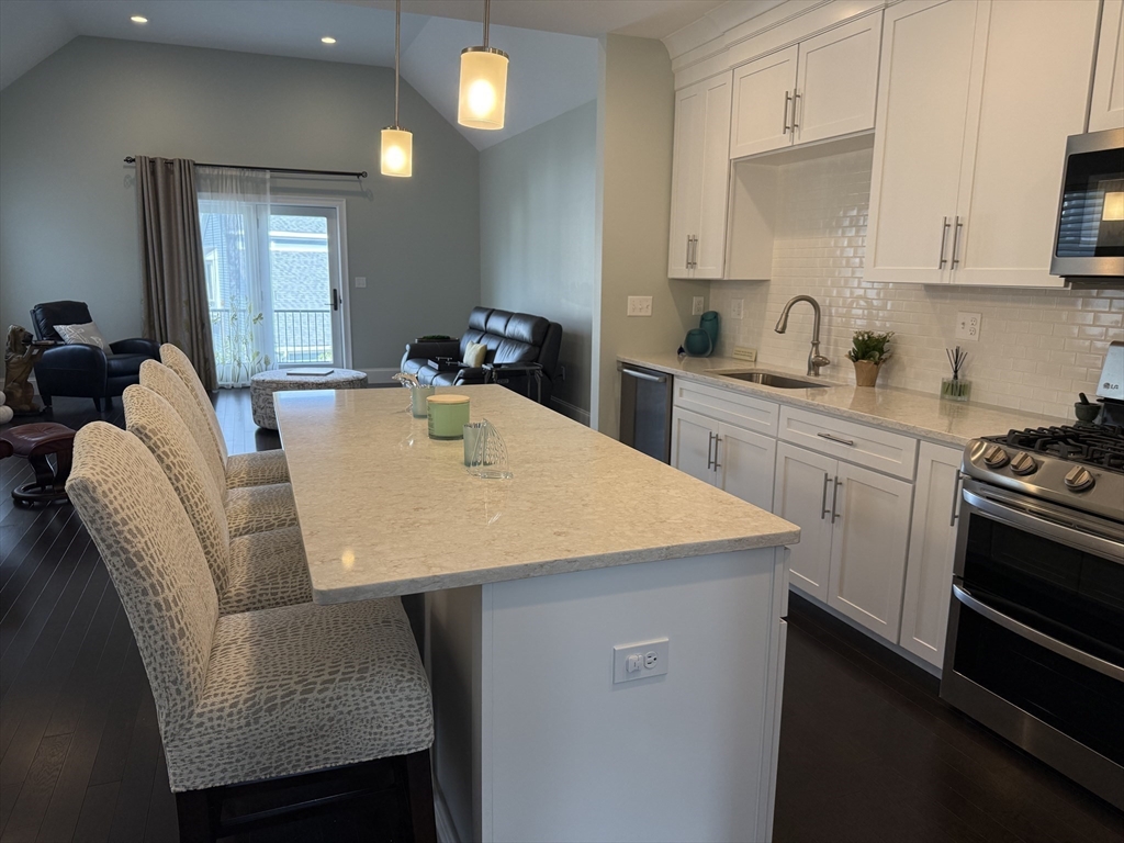 13 Birkdale Lane, Unit 13 Hopkinton, MA 01748 - Photo 3 of 27 a kitchen with stainless steel appliances kitchen island granite countertop a sink a stove a table and chairs