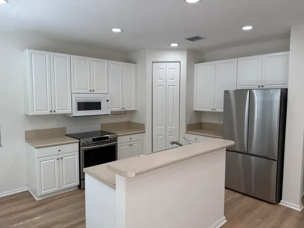 a kitchen with stainless steel appliances a refrigerator sink and white cabinets