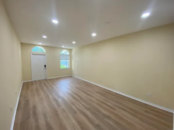 an empty room with wooden floor and windows