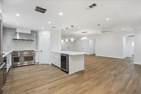 a kitchen with stainless steel appliances kitchen island granite countertop a stove a refrigerator and a sink with wooden floor