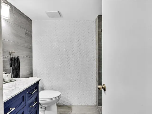 a bathroom with a granite countertop sink toilet and mirror