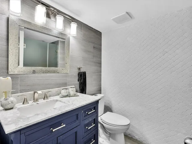 a bathroom with a granite countertop toilet sink and mirror