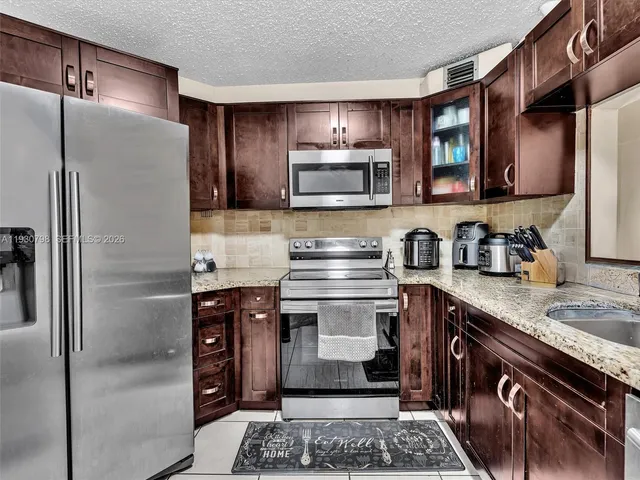 a kitchen with stainless steel appliances granite countertop a stove a refrigerator and a sink