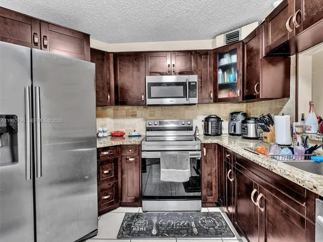 a kitchen with stainless steel appliances granite countertop a refrigerator stove and sink
