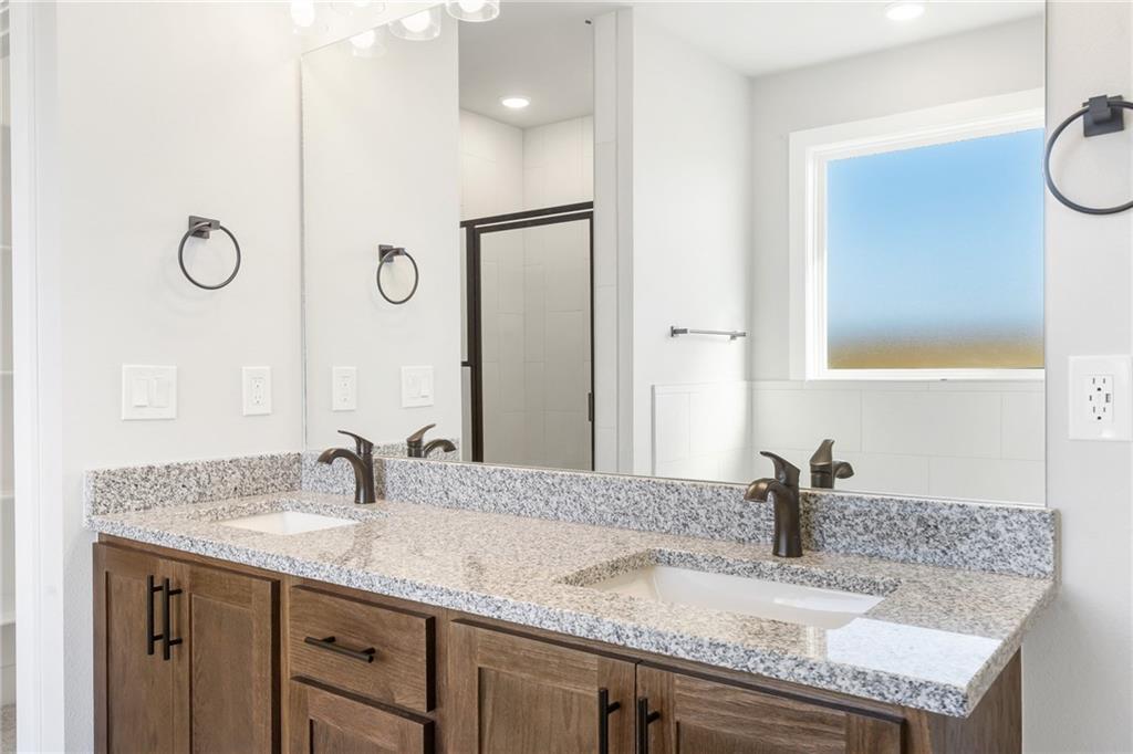 1910 Peacock Road Centerton, AR 72719 - Photo 13 of 29 Double vanity with integrated sinks, granite countertops, wood-finish cabinetry, and matte bronze fixtures