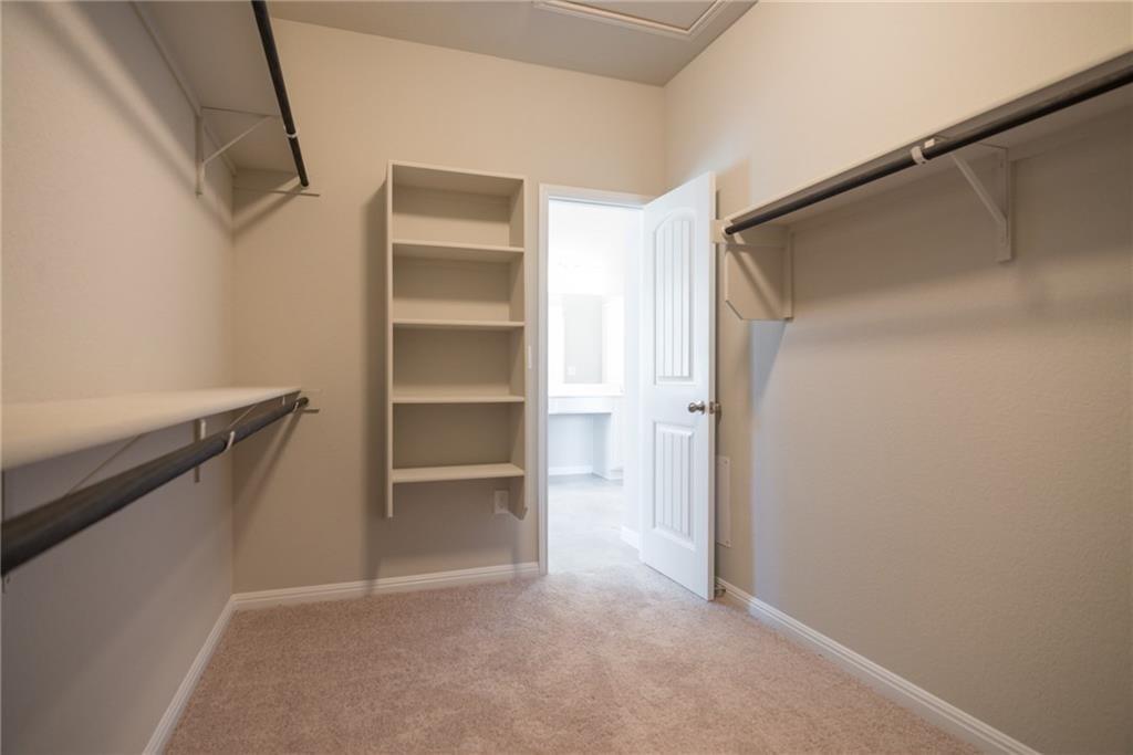 641 Schefer Street Leander, TX 78641 - Photo 12 of 17 Expansive walk-in closet featuring built-in shelving, multiple hanging rods, and plush carpet flooring