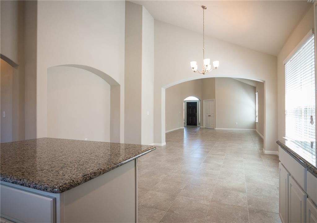641 Schefer Street Leander, TX 78641 - Photo 14 of 17 Kitchen island with a granite-style countertop, featuring recessed panel cabinetry