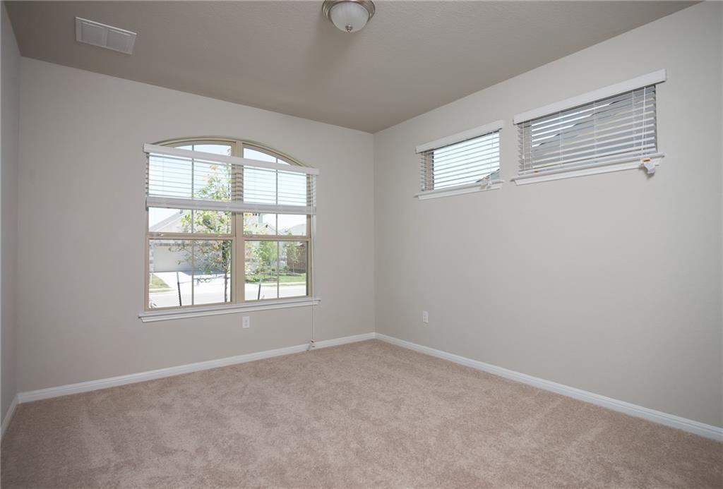 641 Schefer Street Leander, TX 78641 - Photo 15 of 17 Carpeted interior room featuring a large arched window with horizontal blinds, two additional rectangular windows with horizontal blinds, neutral wall paint, and white baseboards