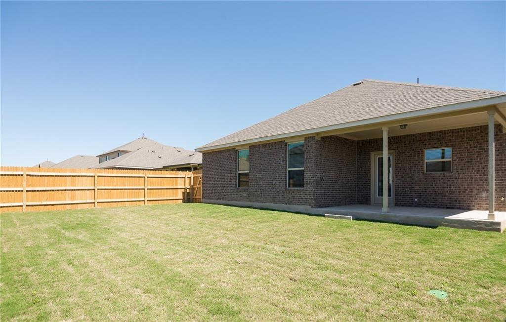 641 Schefer Street Leander, TX 78641 - Photo 16 of 17 Expansive backyard featuring a manicured lawn, a wood privacy fence, and a covered patio with concrete flooring