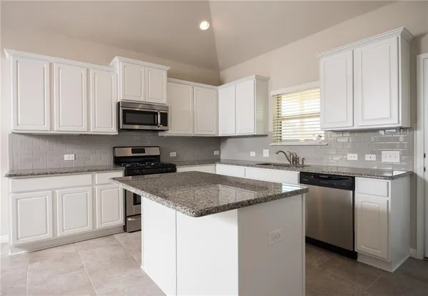 a kitchen with stainless steel appliances granite countertop a sink stove and microwave