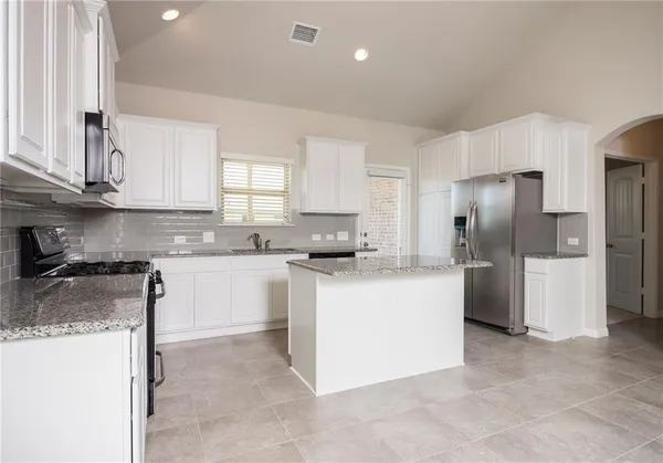 a kitchen with a refrigerator sink and cabinets