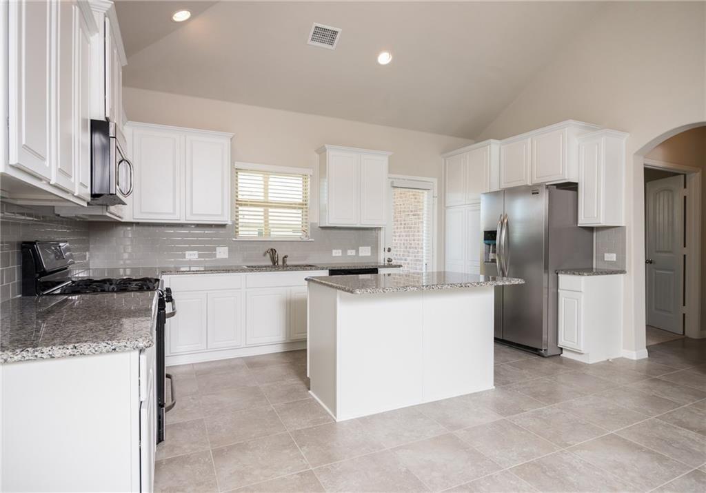 641 Schefer Street Leander, TX 78641 - Photo 7 of 17 Open-concept kitchen featuring white cabinetry, granite countertops, a central island, stainless steel appliances, and a tiled backsplash