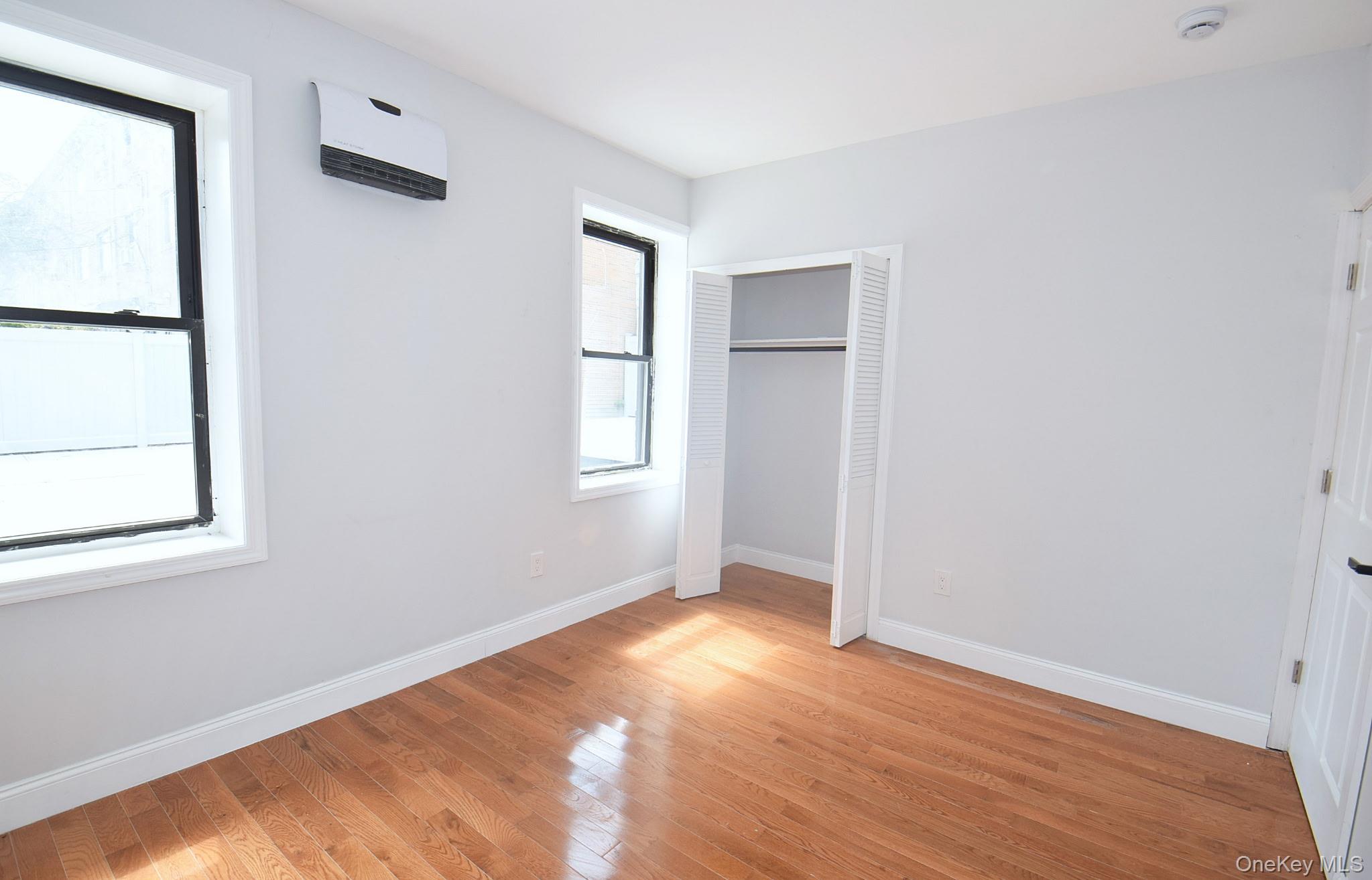 155-20 Tuskegee Airmen Way Queens, NY 11433 - Photo 6 of 13 an empty room with wooden floor and windows