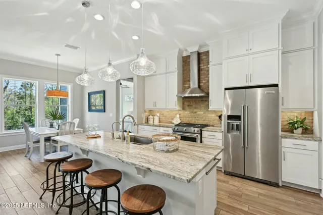 a kitchen with granite countertop a table chairs microwave and refrigerator