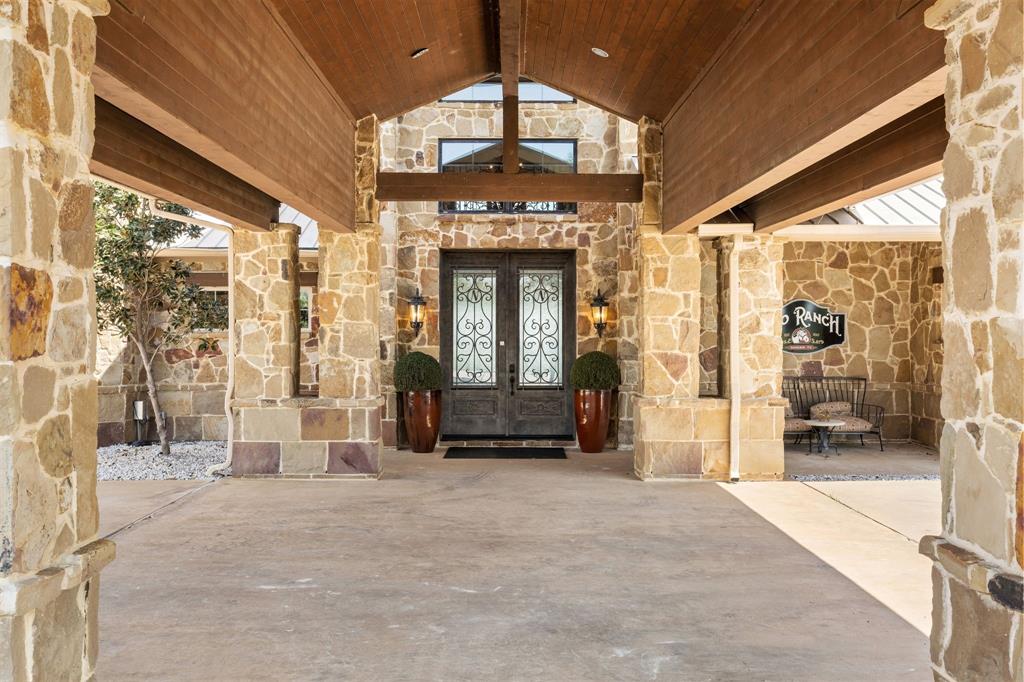 1180 McReynolds Road Sanger, TX 76266 - Photo 7 of 40 Stone masonry facade featuring a covered entry, wood-finish ceiling, double entry doors with decorative ironwork, and exterior lighting fixtures