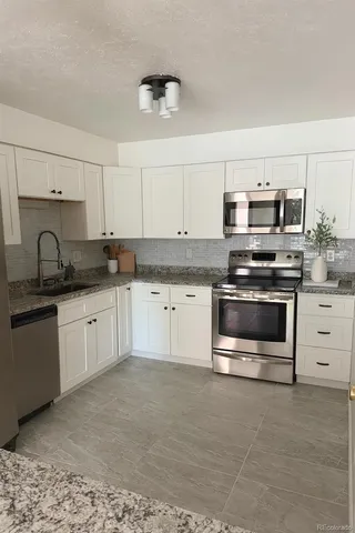 a kitchen with granite countertop white cabinets and stainless steel appliances