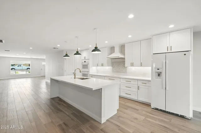 a kitchen with white cabinets appliances and wooden floor