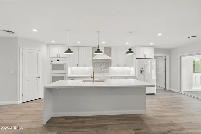 a view of kitchen with white cabinets stainless steel appliances and wooden floor