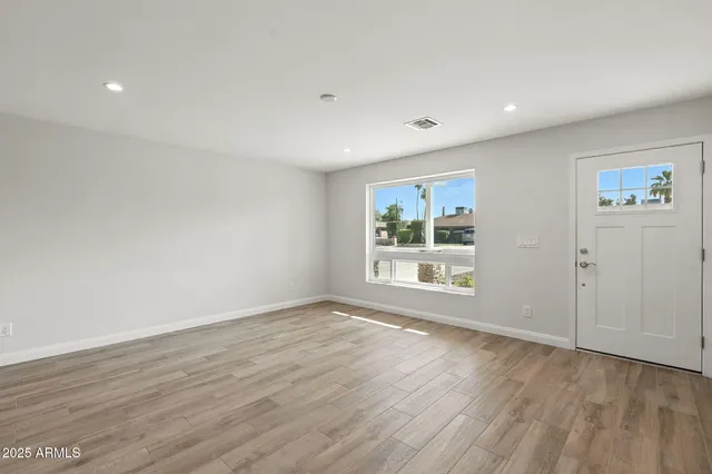 a view of empty room with wooden floor and fan