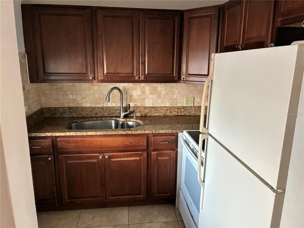 3101 Bee Ridge Road, Unit 214 Sarasota, FL 34239 - Photo 4 of 9 a kitchen with stainless steel appliances granite countertop a refrigerator and a stove top oven