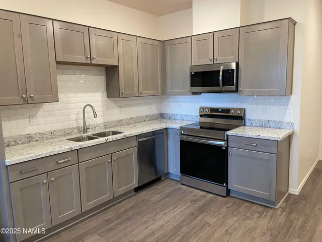 a kitchen with stainless steel appliances granite countertop a sink a stove a microwave and cabinets