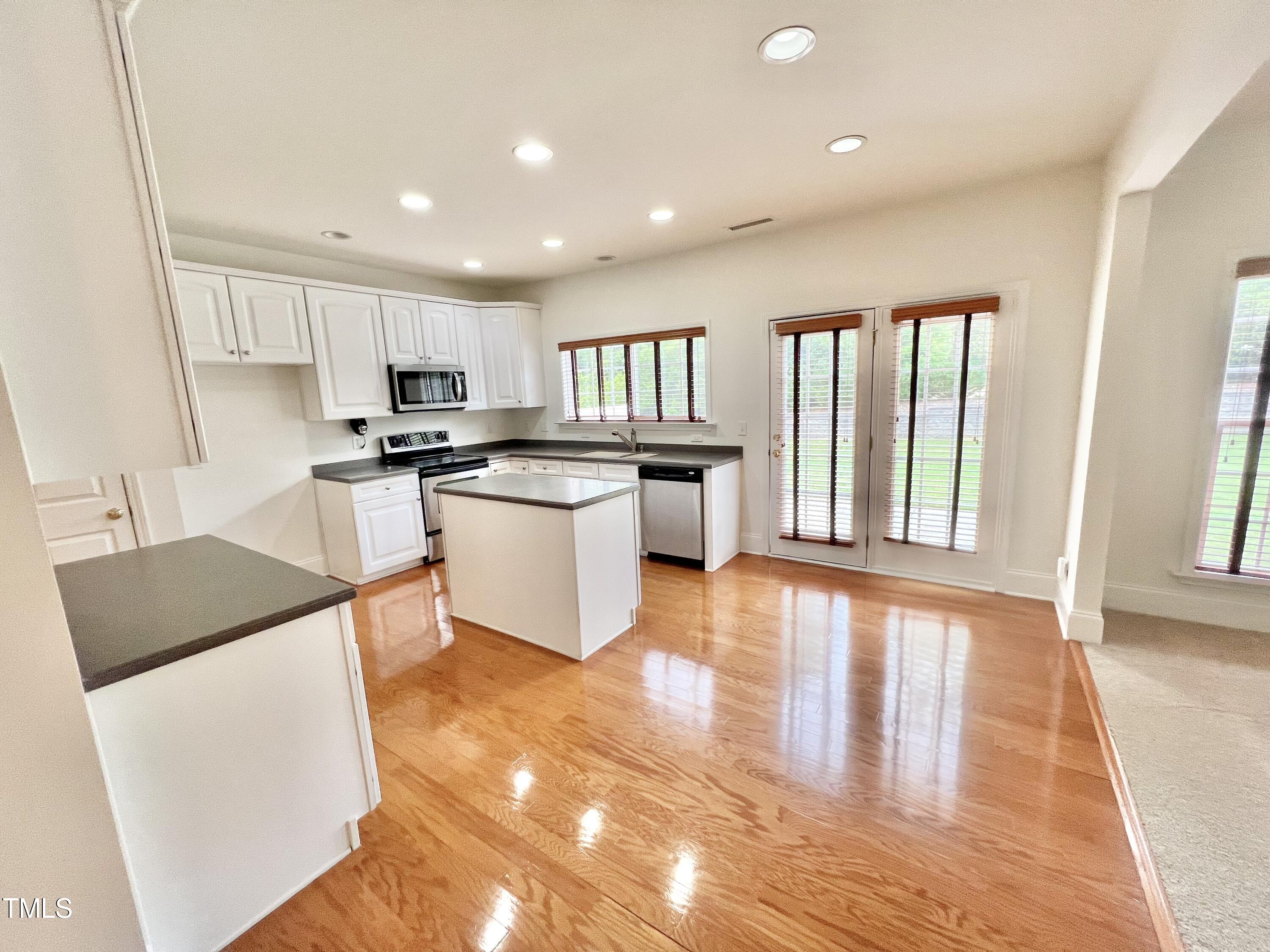 12221 Fox Valley Street Raleigh, NC 27614 - Photo 10 of 29 a kitchen with stainless steel appliances granite countertop a stove a sink dishwasher and a refrigerator with wooden floor