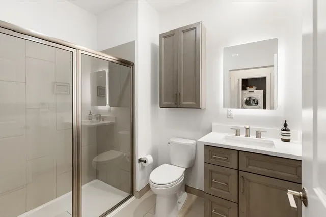a bathroom with a toilet sink vanity and shower