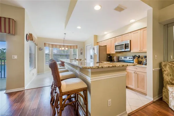a kitchen with stainless steel appliances granite countertop a refrigerator a stove top oven a sink dishwasher and white cabinets with wooden floor