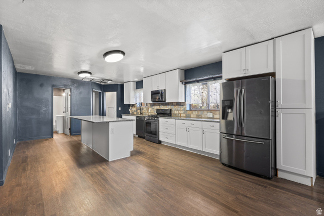 2576 Gramercy Avenue Ogden, UT 84401 - Photo 5 of 20 Kitchen featuring stainless steel appliances, white cabinets, dark wood-type flooring, a kitchen island, and decorative backsplash