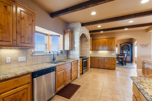 a large kitchen with granite countertop a large counter top a sink stainless steel appliances and cabinets