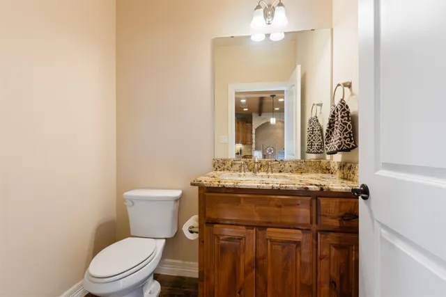 a bathroom with a granite countertop toilet sink and mirror