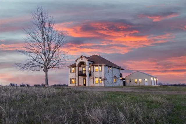 a view of a big house with a big yard and large trees