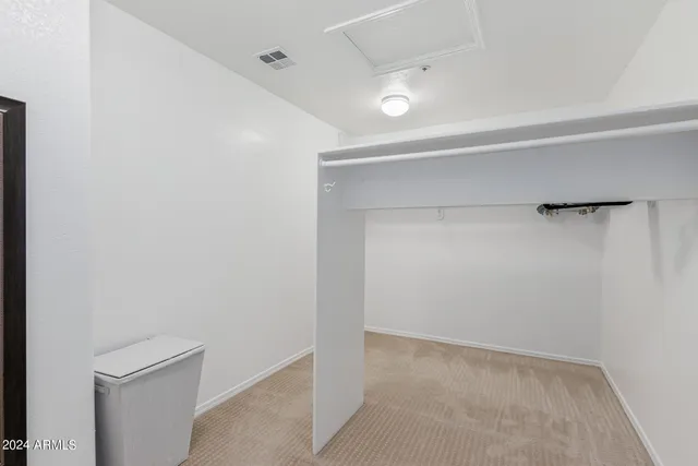 a view of a hallway with white walls and refrigerator
