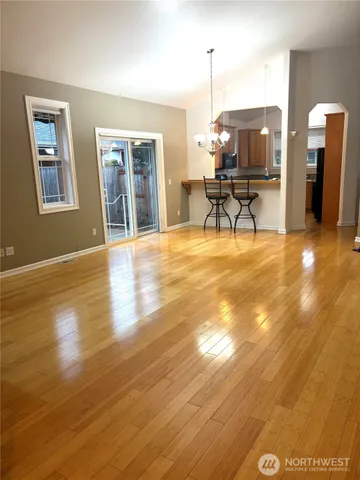 an empty room with wooden floor fireplace and windows