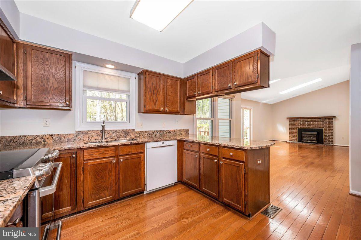 1402 Partridge Lane Bowie, MD 20721 - Photo 13 of 56 a kitchen with stainless steel appliances granite countertop wooden cabinets a sink dishwasher a stove and a refrigerator with wooden floor
