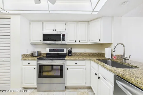 a kitchen with granite countertop a stove sink and cabinets