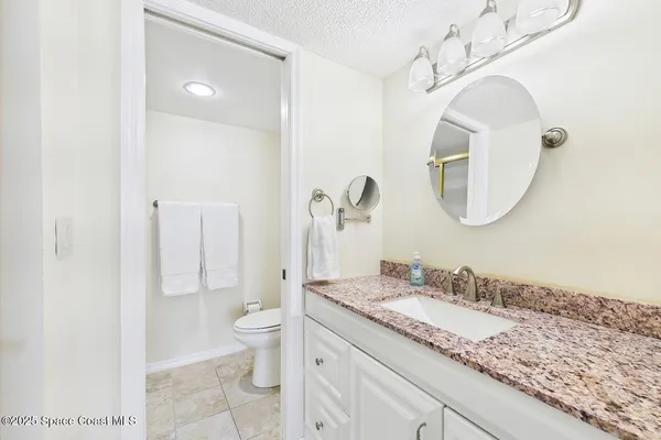 a bathroom with a granite countertop sink a toilet and a mirror